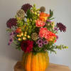 Mixed bouquet in a carved pumpkin vase with orange roses and burgundy blooms