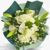 Creamy white hydrangeas, white roses, and petite daisies cluster into a soft