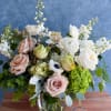 Mixed bouquet of pale roses and white blooms in a glass vase