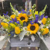 Mixed bouquet with sunflowers, yellow roses, and blue irises in a wooden box