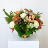 Mixed bouquet of roses and orange blooms in a glass vase