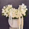 White rose arrangement in a white vase with trailing cream accents