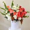 Large floral arrangement with white lilies, red roses, and pink anthuriums in a white box