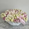 Low floral arrangement of pink and white roses in a white bowl vase