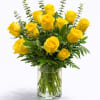 Arrangement of bright yellow roses with greenery in a clear glass vase