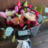 Bouquet of pink tulips, roses, and chrysanthemums wrapped in black paper