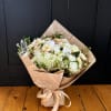 Wrapped bouquet of white and cream flowers tied with a satin ribbon