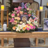 Large funeral flower arrangement with pink, peach, white, and blue blooms