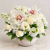 White floral arrangement in a round vase with roses, hydrangeas, and orchids
