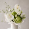White anthuriums and green hydrangeas in a white vase