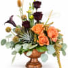 Mixed floral arrangement in a copper vase with orange and dark burgundy blooms