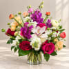 Mixed bouquet of roses, orchids, and white blooms in a glass vase