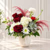 Red roses and white blooms in a white face vase with pink accents