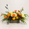Autumn floral arrangement in a rectangular vase with orange, yellow, and dark blooms
