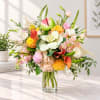 Mixed bouquet in a clear glass vase with pink, white, yellow, and orange blooms