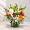 Colorful bouquet in a green glass vase with lilies, roses, orchids, and white blooms