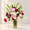 Mixed bouquet of roses, lilies, peonies, and hydrangeas in a clear glass vase