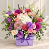 Mixed bouquet of pink, purple, and white flowers in a lavender box