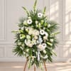 White floral standing spray with lilies, roses, and daisies on an easel