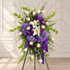 Tall floral standing spray with white lilies, cream roses, and purple blooms