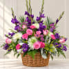 Pink and purple mixed flower arrangement in a wicker basket