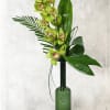 This elegant design includes a full cymbidium orchid stem, with tropical foliage.