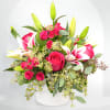 Pink roses and white lilies arranged in a white vase