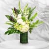 White roses and green orchids in a tall glass vase