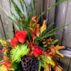 Autumn floral arrangement with red roses and mixed foliage in a vase