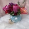 A sweet and charming arrangement featuring delicate flowers and fresh seasonal foliage
