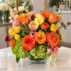 Bright mixed bouquet of roses, hydrangeas, and carnations in a glass vase