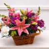 Basket arrangement with pink lilies, purple daisies, and white carnations