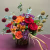 Mixed bouquet of red, orange, and purple flowers in a rustic vase