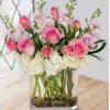 Pink roses and tulips in a clear glass vase with white blooms