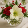 Red roses and a white amaryllis in a clear glass bowl