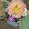 Small boutonniere with a pale peach flower and purple accents