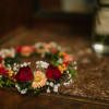 Floral crown with red roses and peach daisies on a table