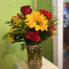Bouquet of sunflowers, red roses, and carnations in a glass vase