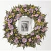 Floral wreath with pink and lavender flowers around a framed photo