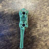 A small teal plastic floral pick on a wooden surface