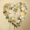 Heart-shaped floral wreath on an easel with pastel roses and white blooms