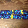 Blue and purple flower lei with yellow rose accents on a wooden surface