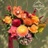Bright orange and pink floral arrangement in a glass vase