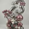 Silver and pink balloon arrangement with large number balloons and a crown topper