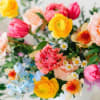 Colorful mixed bouquet with yellow, pink, peach, and blue flowers