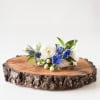 Small white and blue floral arrangement on a wood slice