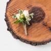 Small white boutonniere with berries on a wood slice
