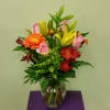 Mixed bouquet of lilies, roses, and gerbera daisies in a glass vase