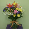 Mixed bouquet of lilies, roses, and carnations in a glass vase
