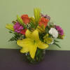 Mixed bouquet with yellow lilies, orange roses, and pink carnations in a glass vase